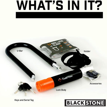 The image showcases a product set that includes a U-bar bike lock by Crystal Vision with a vibrant orange lock body, a set of keys attached to a serial tag, a holder for the lock, and additional accessories, all under the brand Black Stone. The items are arranged against a white background for a clear view of the components included in the purchase. The text "What's in it?" is prominently displayed, guiding viewers to the contents of the package